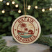 A circular ornament with the text "GILI AIR INDONESIA" and a palm tree design, hanging from a string against a background of Christmas lights and greenery.