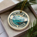 A circular ornament with the text "GLACIER BAY NATIONAL PARK" printed on it, surrounded by pine branches.