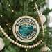 A Christmas tree decorated with ornaments, including a circular ornament with the text "GLACIER BAY NATIONAL PARK" and a scenic mountain landscape.