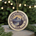 A circular ornament with the text "GLACIER NATIONAL PARK USA" and a mountain landscape design, hanging from a string.