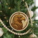 A Christmas tree decorated with ornaments, including a circular ornament featuring a close-up of a golden eagle's head.