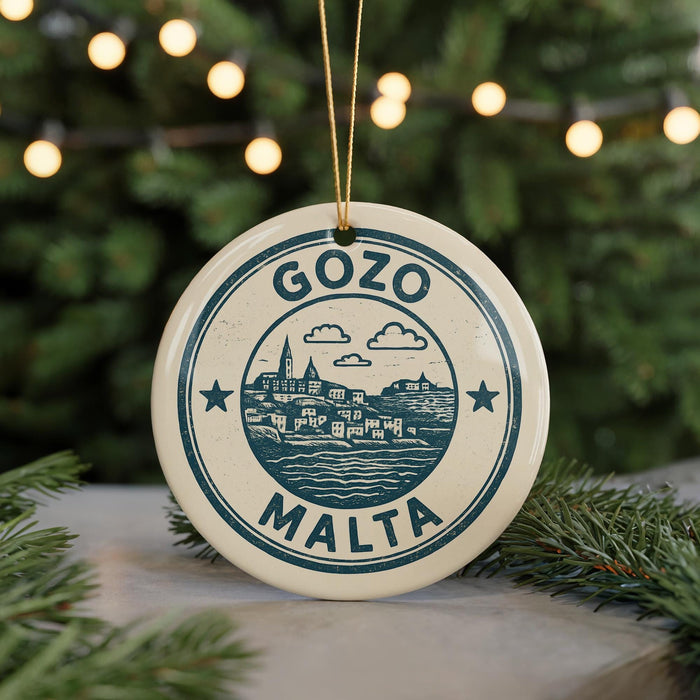 A circular ornament with the text "GOZO MALTA" and a graphic of a cityscape, hanging from a string against a background of Christmas lights and greenery.