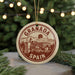 A circular ornament with the text "GRANADA SPAIN" printed on it, featuring an illustration of a castle and mountains.