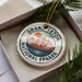 A circular ornament with the text "GRAND Teton NATIONAL FPAARK" printed on it, surrounded by pine branches.