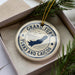 A circular ornament with the text "GRAND TURK TURKS AND CAICOS" printed on it, surrounded by pine branches.