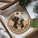 A round ornament featuring a dog's head and the text "GREATER SWISS MOUNTAIN DOG" is displayed in a box with pine branches.