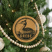 A Christmas tree decorated with ornaments, including a circular ornament with a duck and the word "GREBE" written on it.