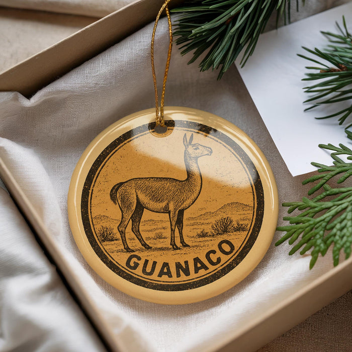 A round ornament with a graphic of a llama and the word "GUANACO" printed on it, hanging from a string.
