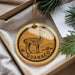 A round ornament with a graphic of a llama and the word "GUANACO" printed on it, hanging from a string.