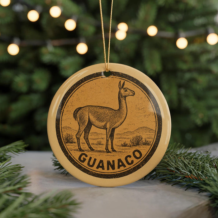 A round ornament with a graphic of a llama and the word "GUANACO" on it, hanging from a string.