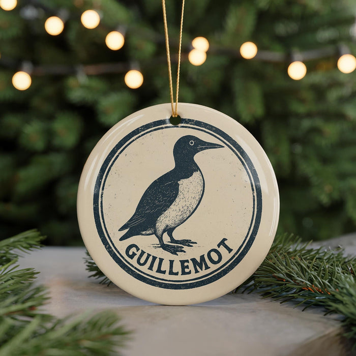 A circular ornament featuring a black and white illustration of a bird, with the text "GUILLLEMOT" prominently displayed.