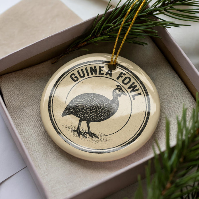 A decorative ornament in a box, featuring a black and white illustration of a guinea fowl.