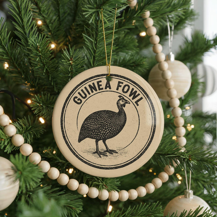 A Christmas tree decorated with ornaments, including a circular ornament with a graphic of a bird and the text "GUINEA FOWL" on it.
