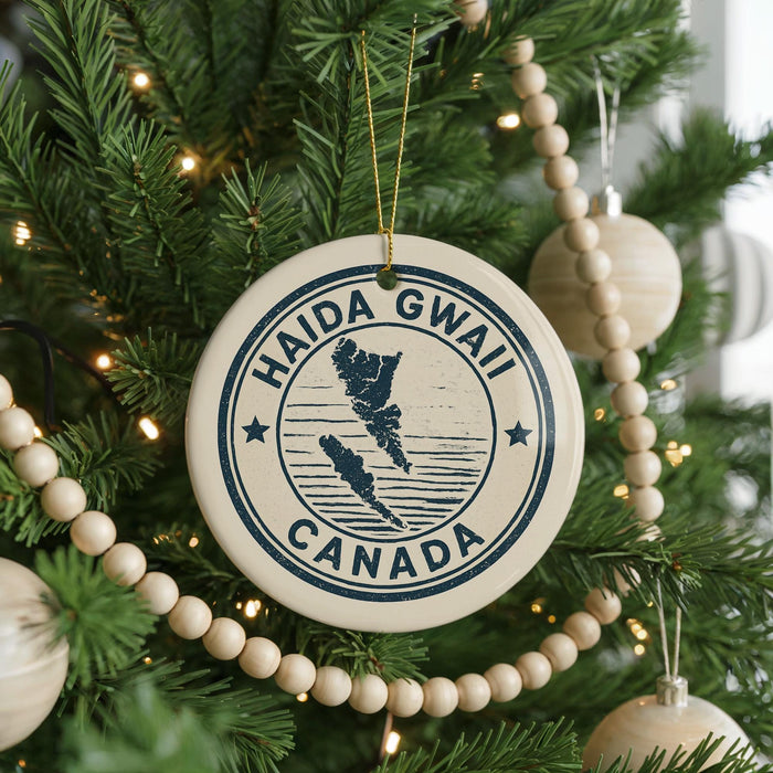 A Christmas tree decorated with ornaments, including a circular ornament with the text "HAIDA GWAI CANADA" and a wooden bead decoration.