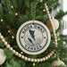 A Christmas tree decorated with ornaments, including a circular ornament with the text "HAIDA GWAI CANADA" and a wooden bead decoration.