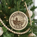 A circular ornament on a Christmas tree, featuring a design of a pagoda and mountains, with the text "HANGSZHOU CHINA" printed on it.
