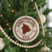 A Christmas tree decorated with ornaments, including a circular ornament with the text "HAWAII'I ISLAND USA" and a wooden bead decoration.