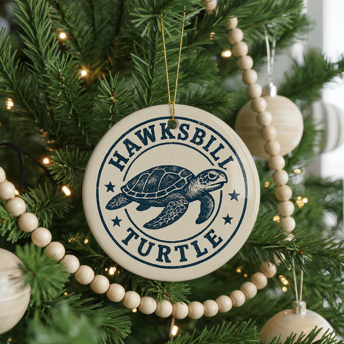 A circular ornament on a Christmas tree, featuring a turtle design and the text "HAWKSBILLI TURTLE".