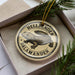 A circular ornament with the text "HELLBENDER SALAMANDER" printed on it, featuring an illustration of a salamander.