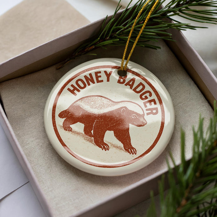 A circular ornament with the text "HONEY BADGER" printed on it, featuring a depiction of a honey badger.