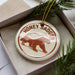 A circular ornament with the text "HONEY BADGER" printed on it, featuring a depiction of a honey badger.