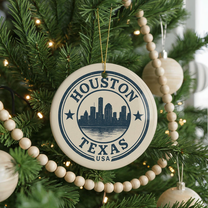 A circular ornament on a Christmas tree with the text "HOUSTON TEXAS USA" printed on it, surrounded by other ornaments and lights.