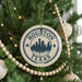 A circular ornament on a Christmas tree with the text "HOUSTON TEXAS USA" printed on it, surrounded by other ornaments and lights.