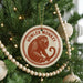 A Christmas tree decorated with ornaments, including a round ornament with a monkey image and the text "HOWLER MONKEY" on it.