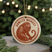 A round ornament featuring a monkey with an open mouth, hanging from a string.