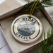 A decorative ornament with the text "HYDRA GREECE" printed on it, surrounded by pine branches.