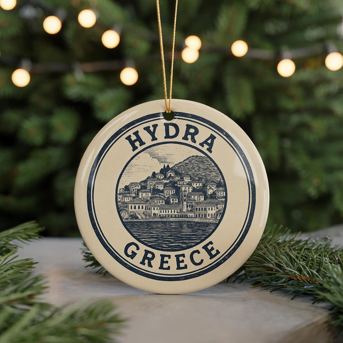 A round ornament with the text "HYDRA GREECE" and an illustration of a town or village, hanging from a string.