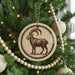 A Christmas tree decorated with ornaments, including a circular ornament featuring a goat and a string of wooden beads.