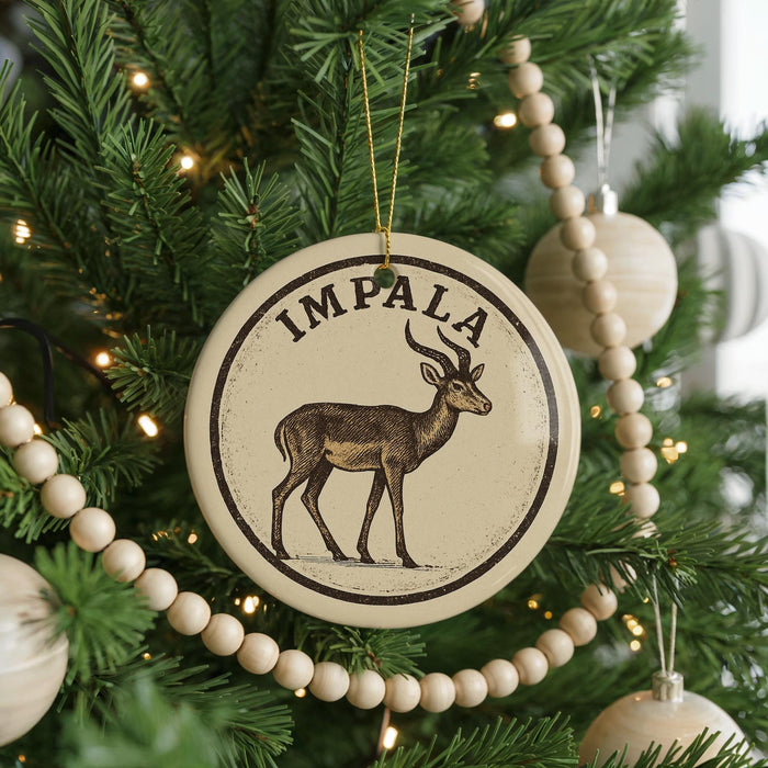 A Christmas tree decorated with ornaments, including a circular ornament with an illustration of a gazelle and the word "IMPA" on it.