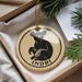 A circular ornament with a bear image and the word "INDRI" printed on it, placed on a surface with pine branches and a white paper.