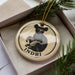 A circular ornament with a black bear image and the word "INDRI" written on it, placed inside a box with pine branches.