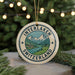 A round ornament with a mountain landscape and Swiss flag design, hanging on a string.