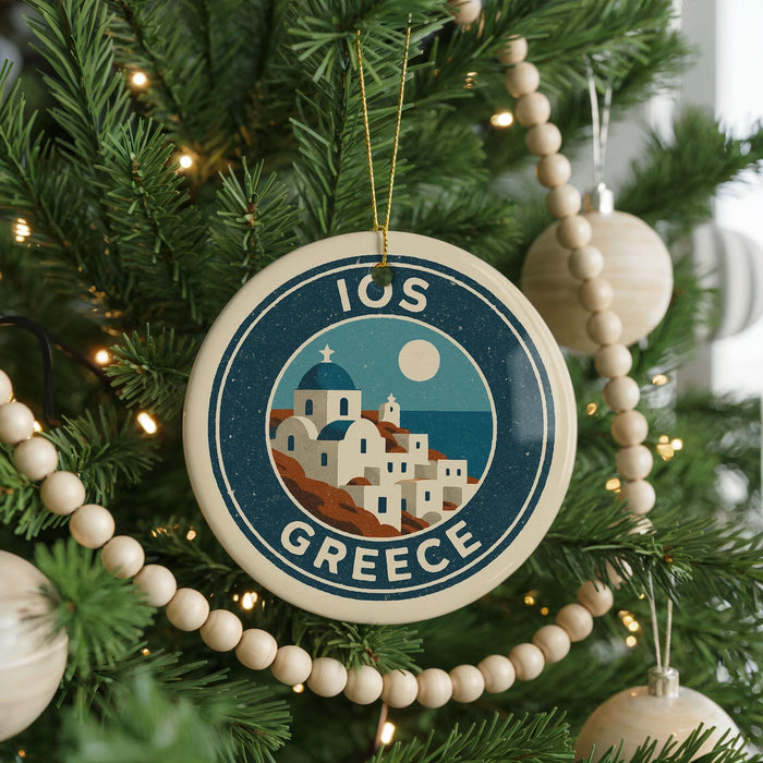 A circular ornament on a Christmas tree, featuring a design of a Greek island with a church and a full moon.
