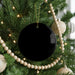 A Christmas tree decorated with ornaments, including a black ornament hanging from the branches.