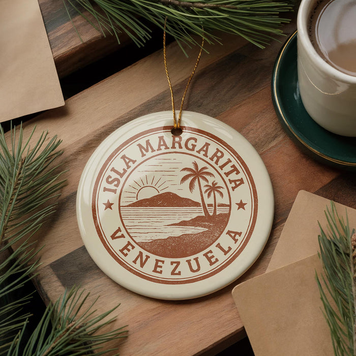 A circular ornament with the text "ISLA MARGARITA VENEZUELA" printed on it, surrounded by pine branches and a cup of coffee on a wooden surface.