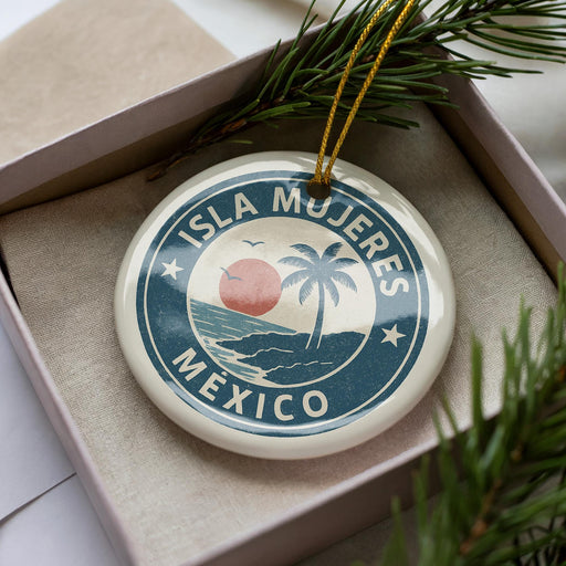 A circular ornament with the text "ISLA MÚJERES MEXICO" printed on it, surrounded by a palm tree and a sunset.