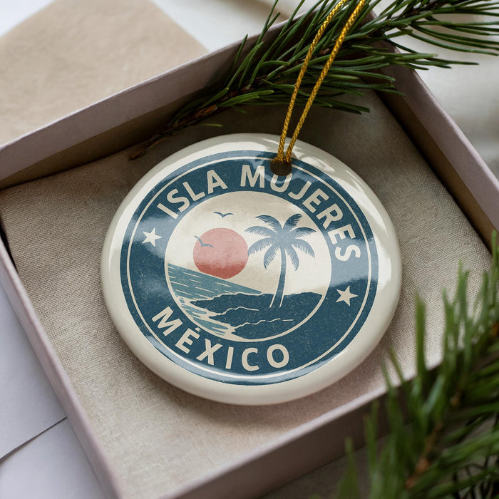 A circular ornament with the text "ISLA MÚJERES MEXICO" printed on it, surrounded by a palm tree and a sunset.