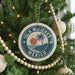 A Christmas tree decorated with ornaments, including a circular ornament with the text "ISLA MUEJERES MEXICO" and a palm tree design.