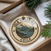 A circular ornament with the text "ISLA NAVARINO CHILE" printed on it, surrounded by a scenic mountain landscape.