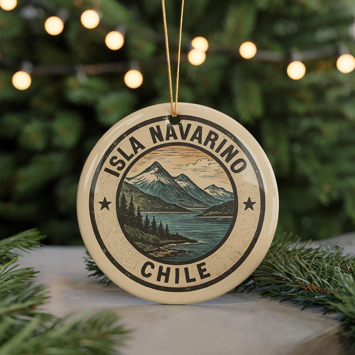 A circular ornament with the text "ISLA NAVARINO CHILE" and a mountain landscape design, hanging from a string against a background of Christmas lights and greenery.