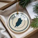A decorative ornament with the text "ISLE OF MAN" and a silhouette of the island of Man, placed in a box with pine branches.