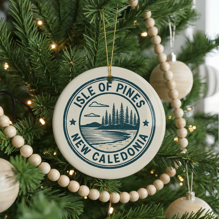 A Christmas tree decorated with ornaments, including a circular ornament with the text "ISLE OF PINES NEW CALEDONIA" and a landscape design.