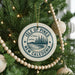 A Christmas tree decorated with ornaments, including a circular ornament with the text "ISLE OF PINES NEW CALEDONIA" and a landscape design.