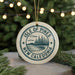 A circular ornament with the text "ISLE OF PINES NEW CALEDONIA" printed on it, surrounded by pine branches and lights.