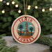 A circular ornament with the text "Izmir Turkey" and an illustration of a tower surrounded by palm trees, placed on a surface with pine branches in the background.