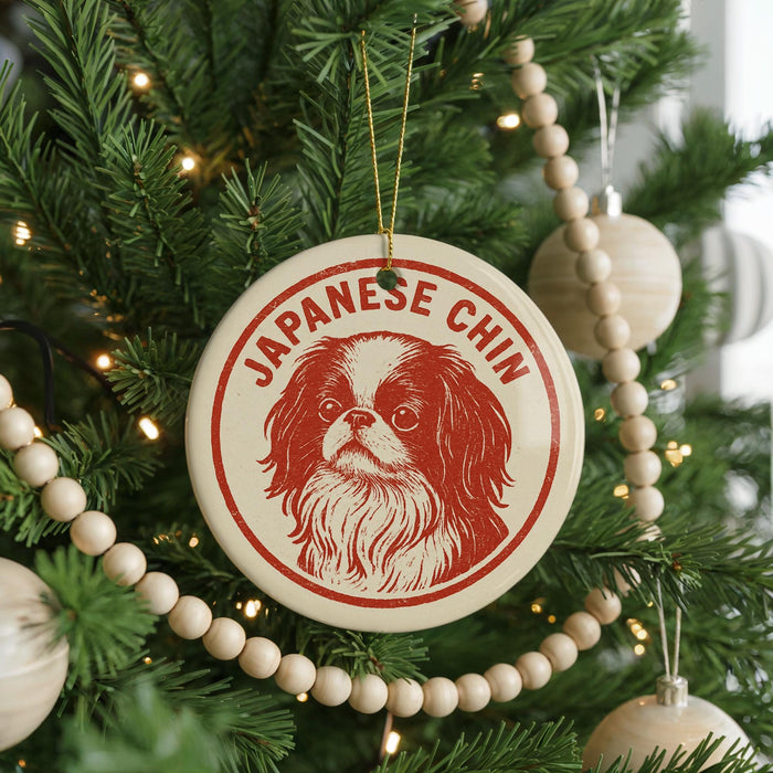 A Christmas tree decorated with ornaments, including a circular ornament with a picture of a Japanese Chin dog and the text "JAPANESE CHIN" on it.